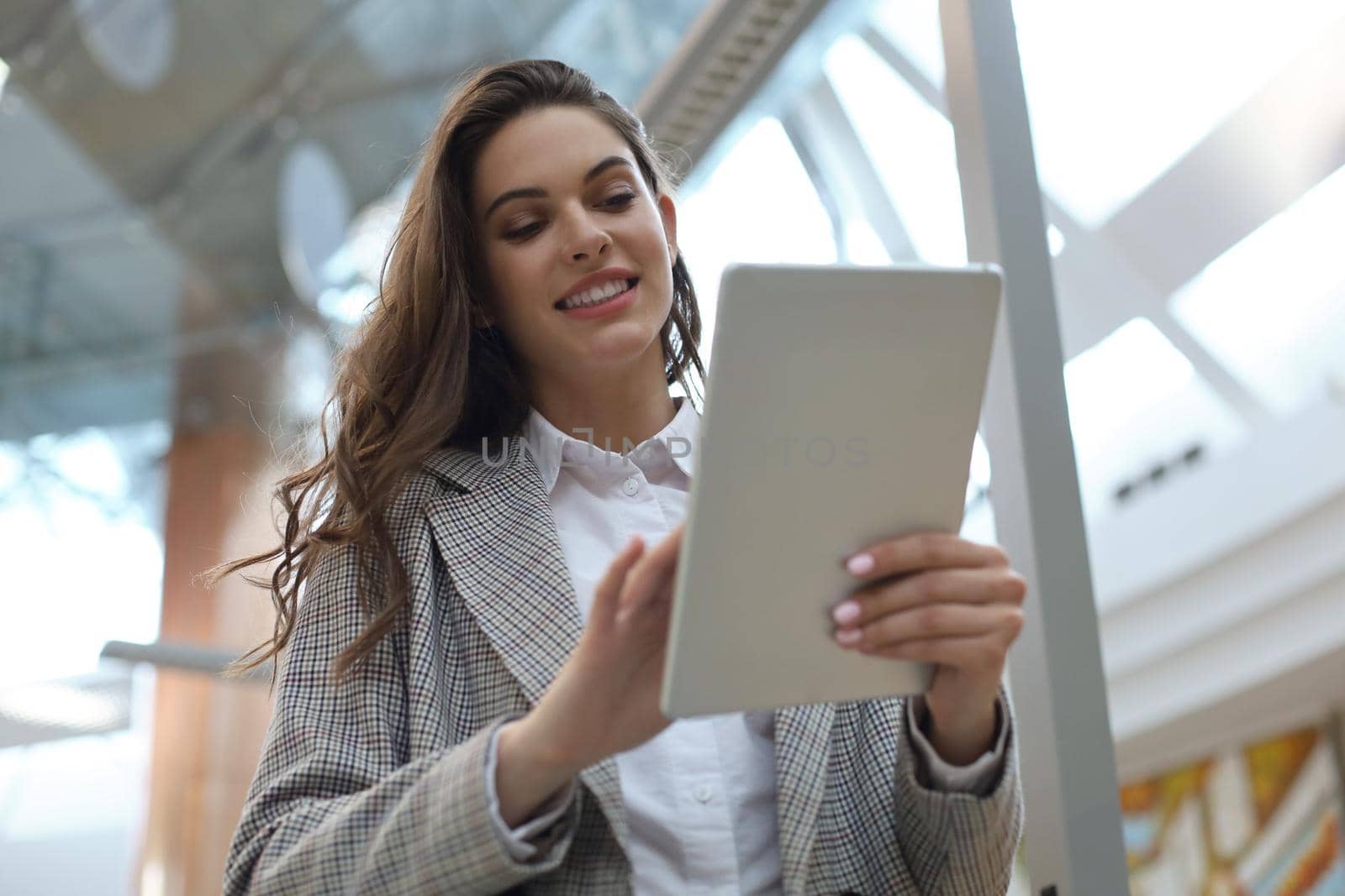 Young smiling businesswoman in office working on digital tablet