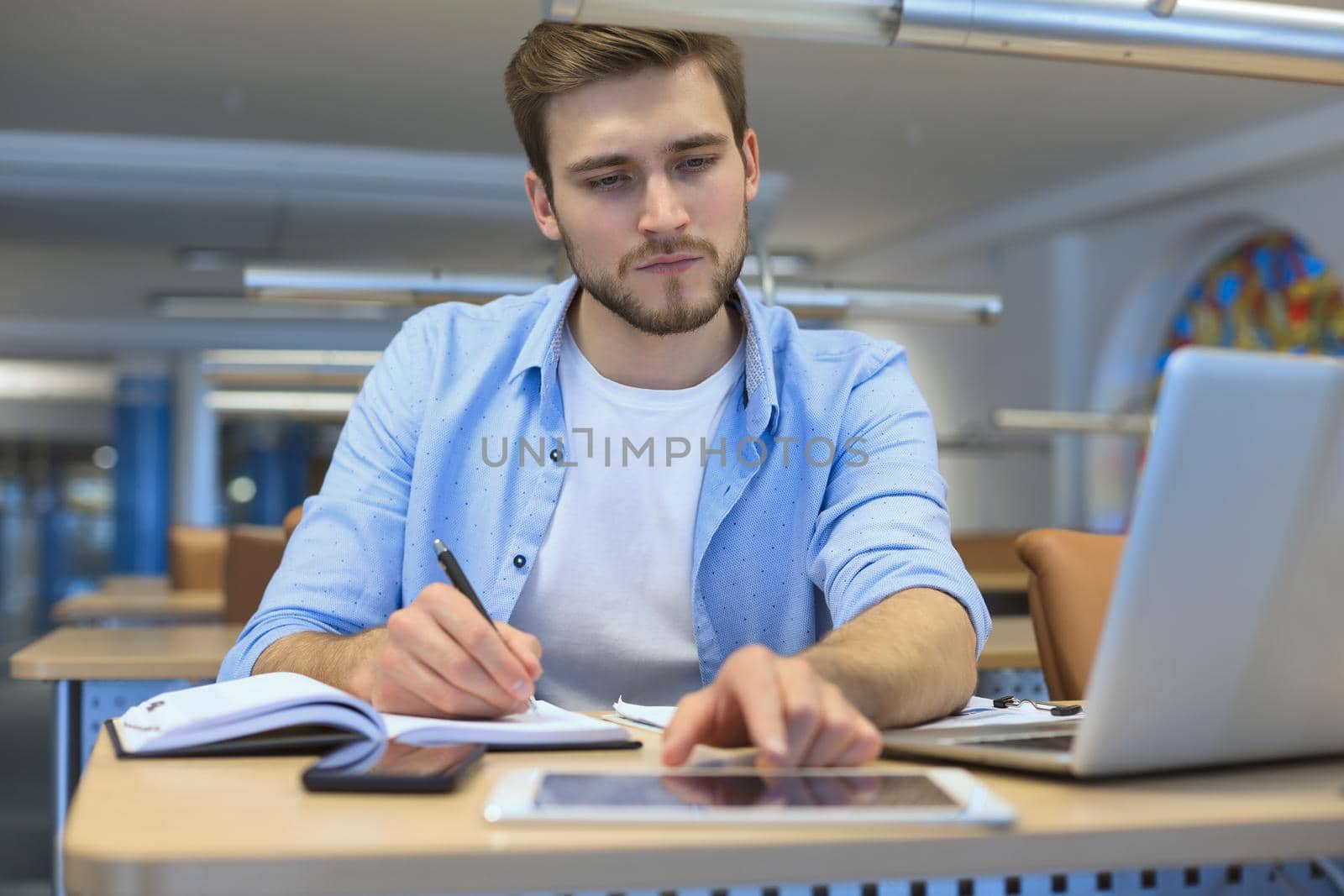 Portrait of young man sitting at his desk in the office. by tsyhun