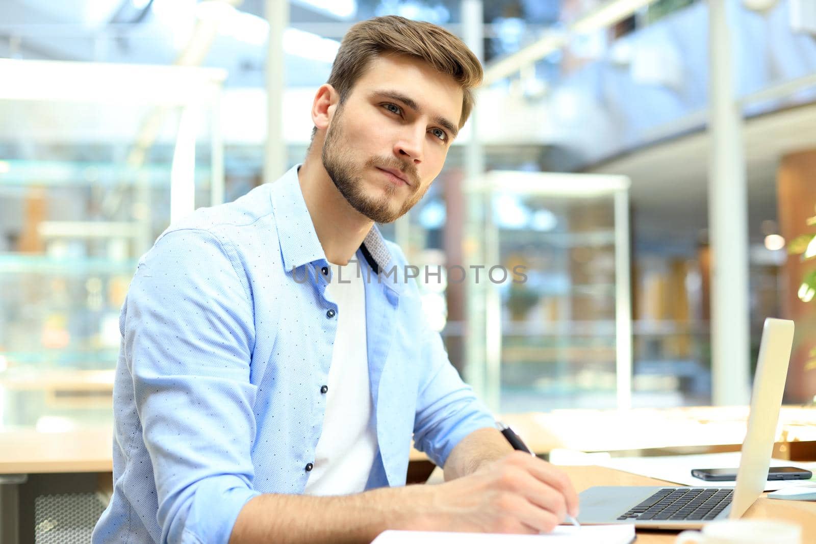 Portrait of young man sitting at his desk in the office. by tsyhun