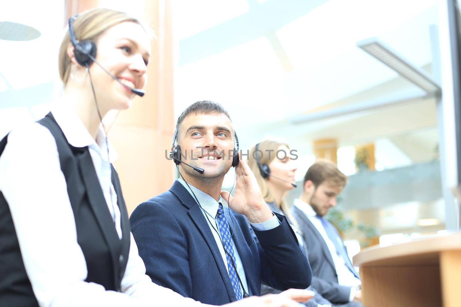 Portrait of call center worker accompanied by his team. Smiling customer support operator at work