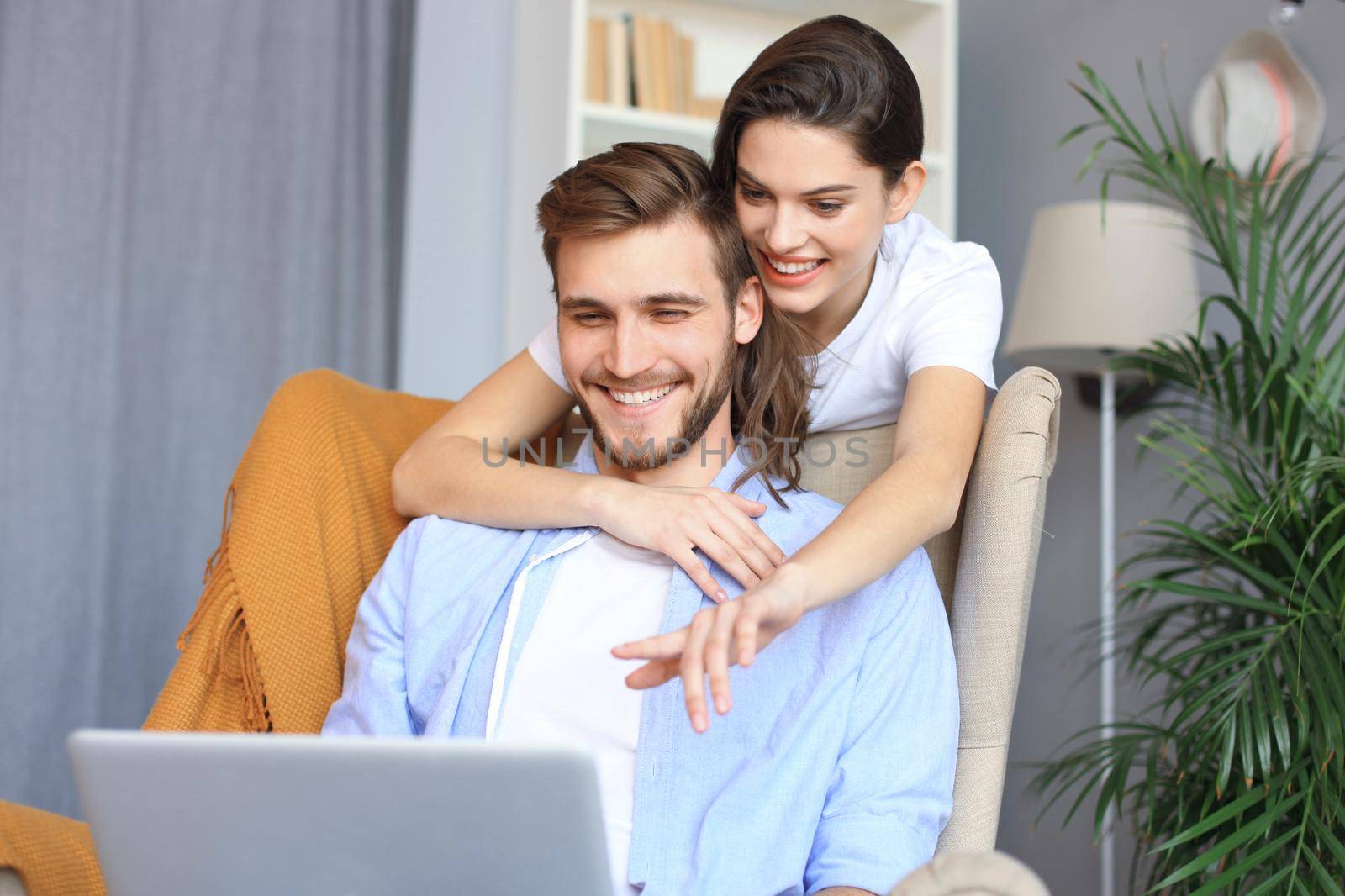 Young couple doing some online shopping at home, using a laptop on the sofa