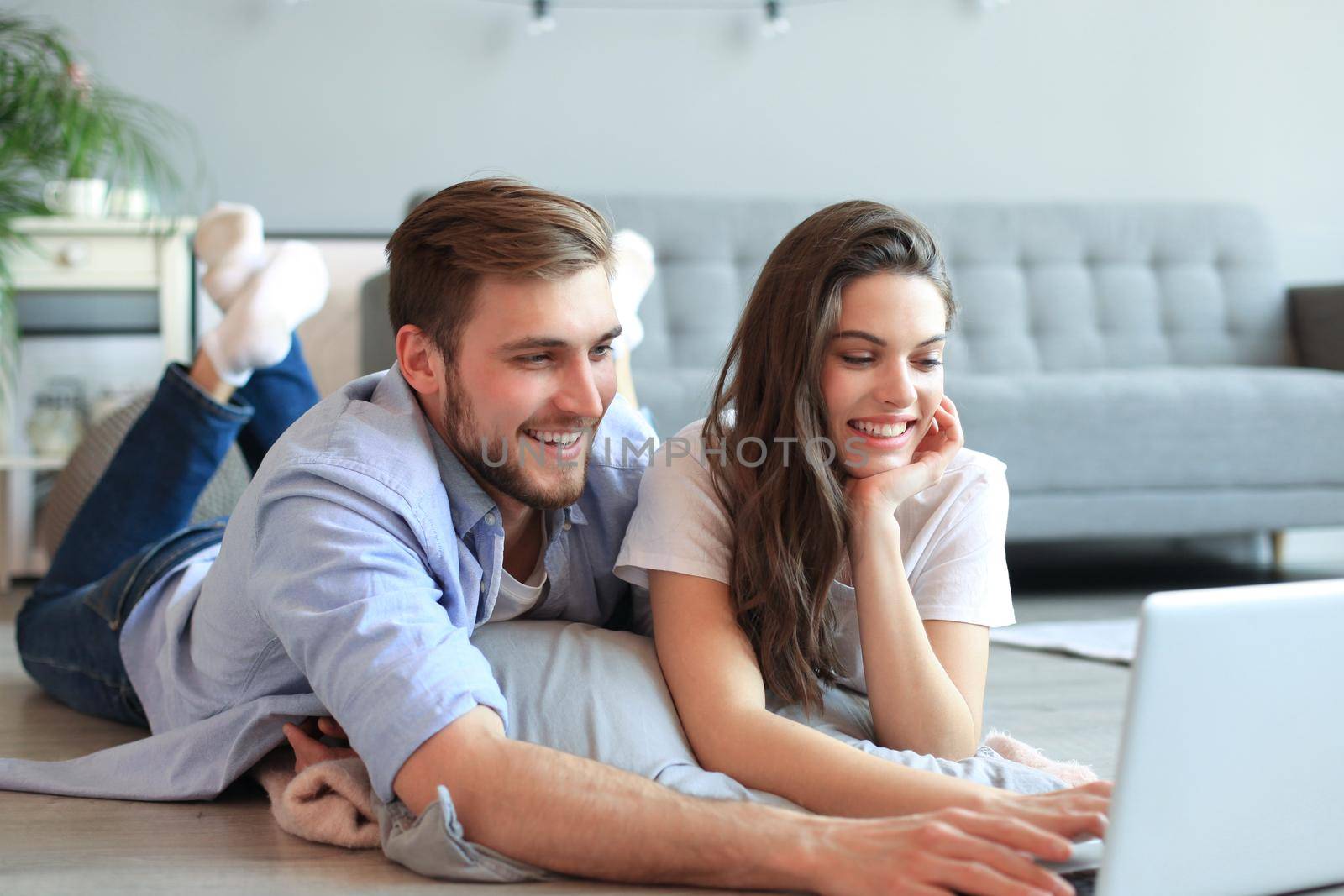 Young couple doing some online shopping at home, using a laptop on floor