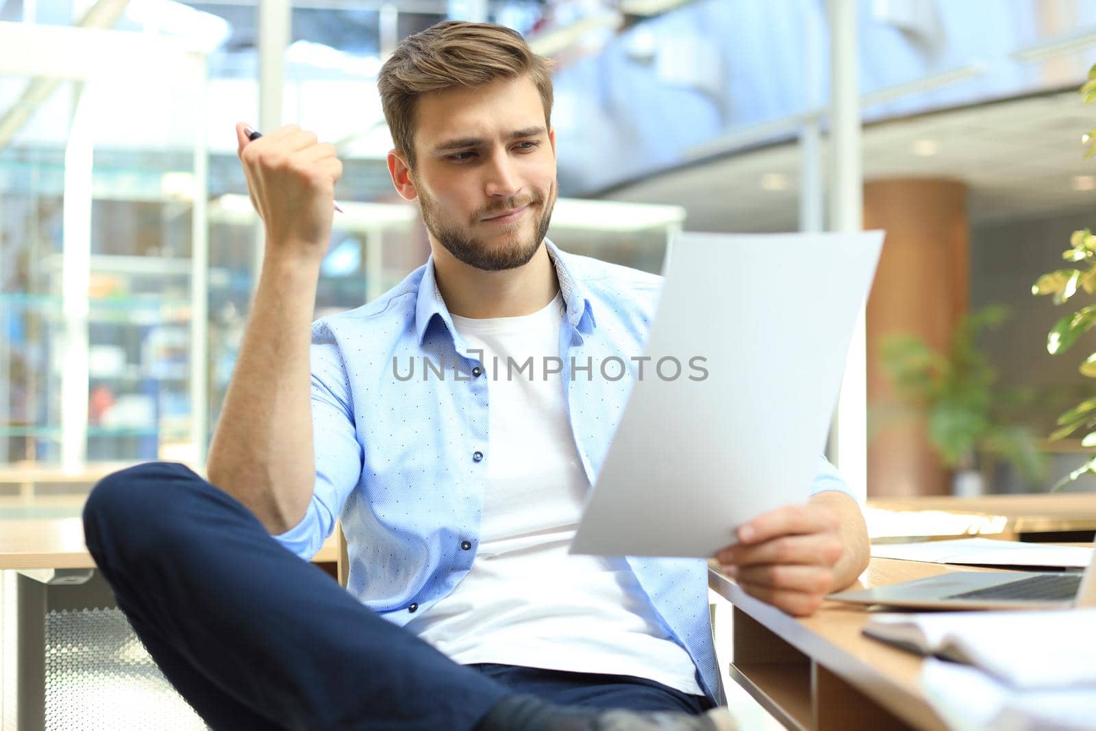 Portrait of young man sitting at his desk in the office. by tsyhun