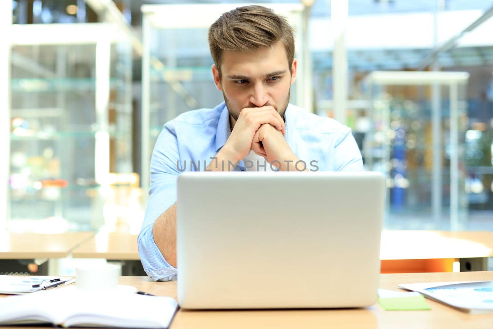 Portrait of young man sitting at his desk in the office