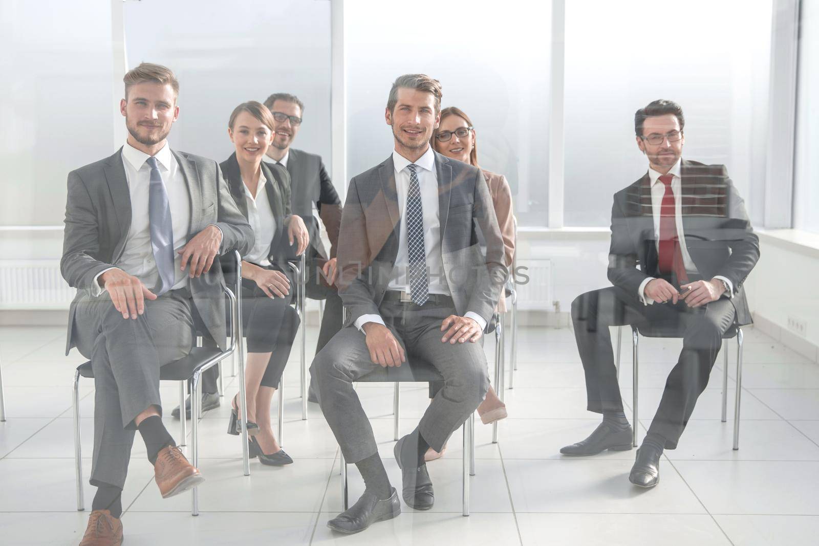 Man and women sitting on chairs in row by asdf