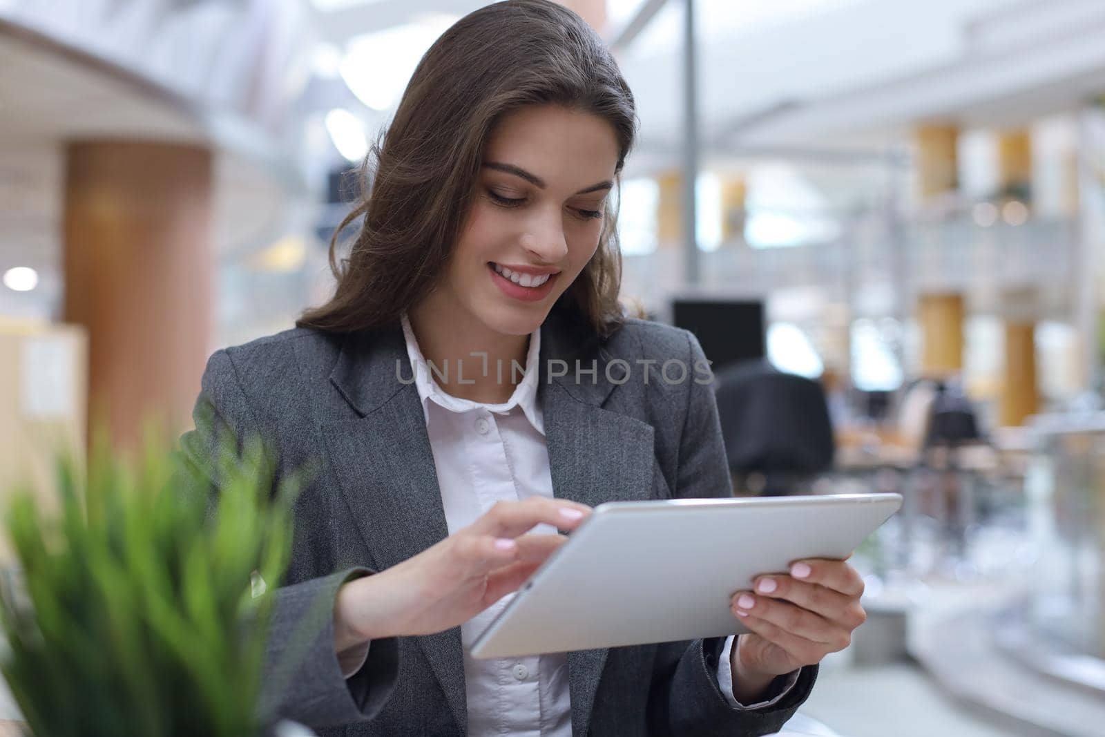 Young smiling businesswoman in office working on digital tablet. by tsyhun