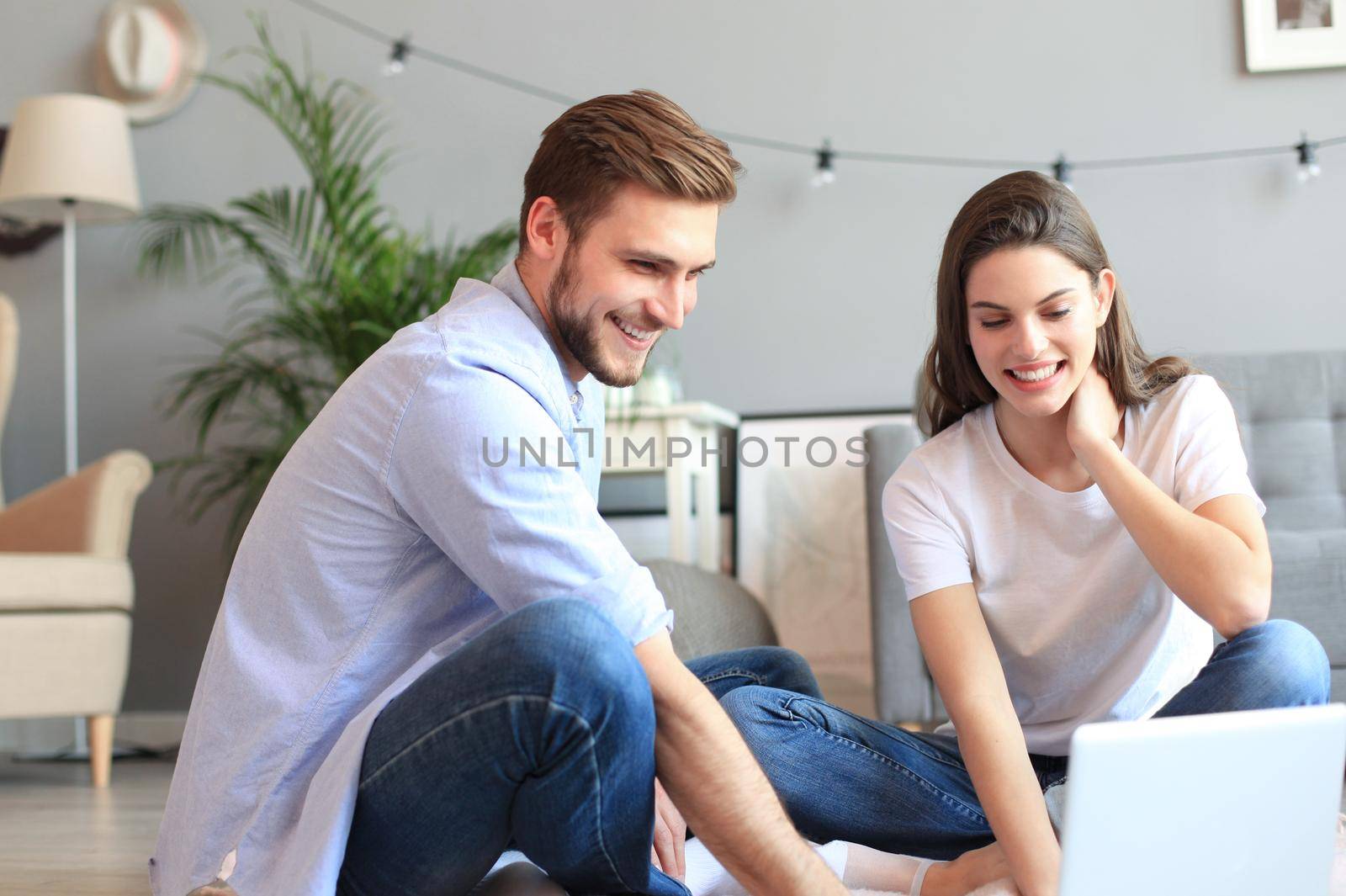 Young couple doing some online shopping at home, using a laptop on floor