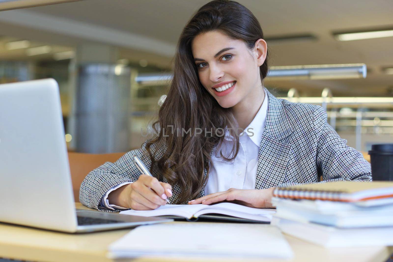 Portrait of a pretty female student with laptop in library