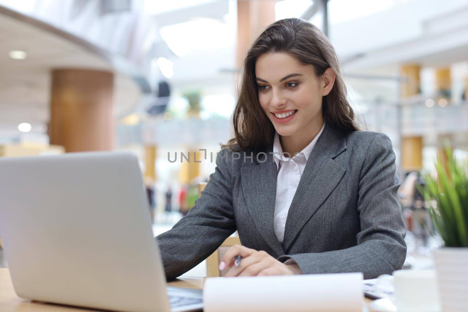 Portrait of a young brunette business woman using laptop at office. by tsyhun