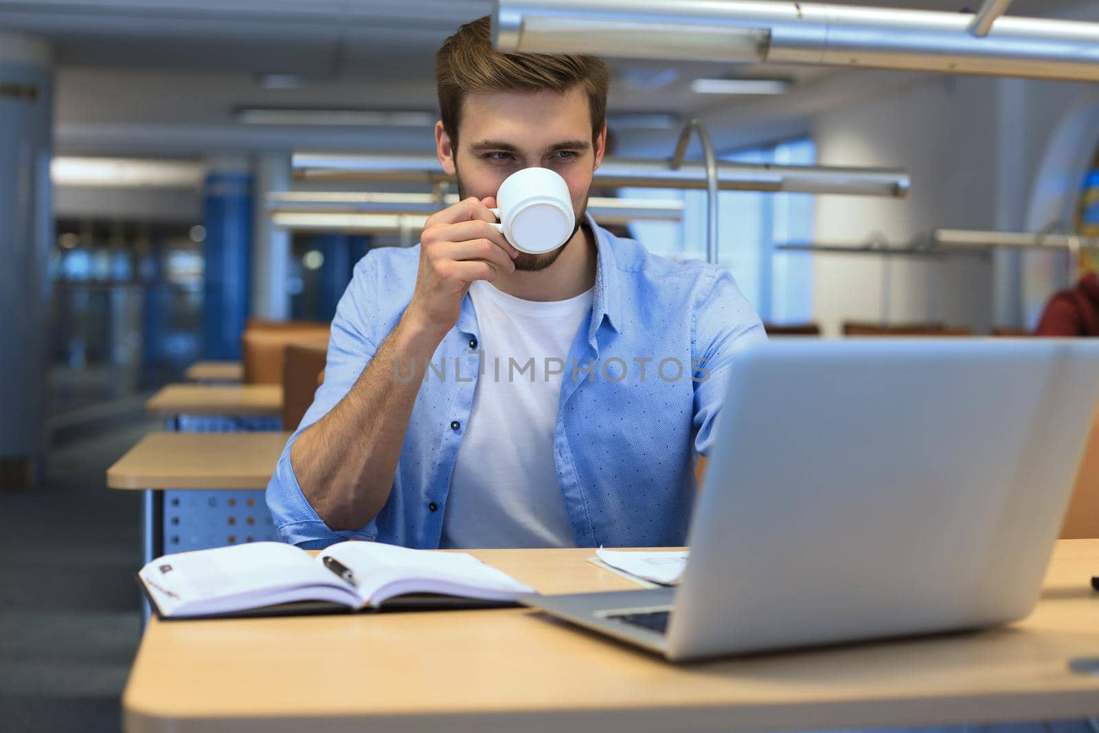 Portrait of young man sitting at his desk in the office. by tsyhun