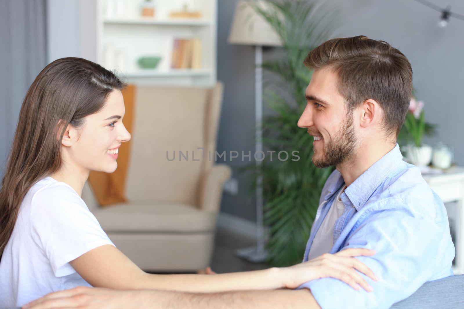 Side view of a couple talking sitting on a couch and looking each other at home