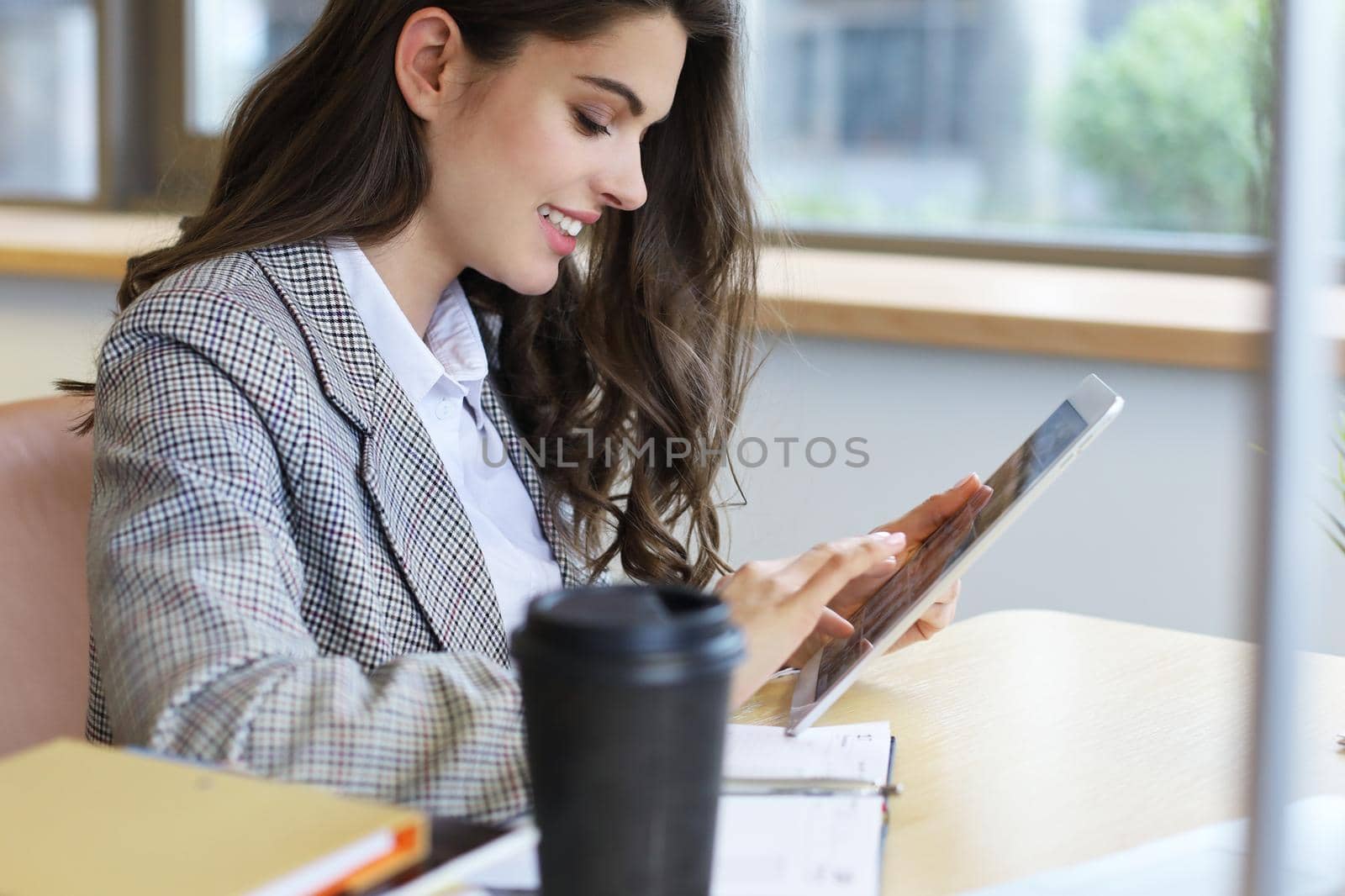 Young smiling businesswoman in office working on digital tablet