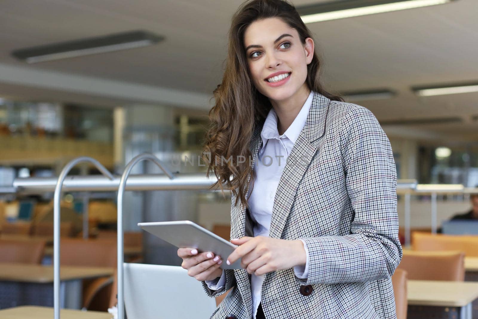 Young smiling businesswoman in office working on digital tablet. by tsyhun