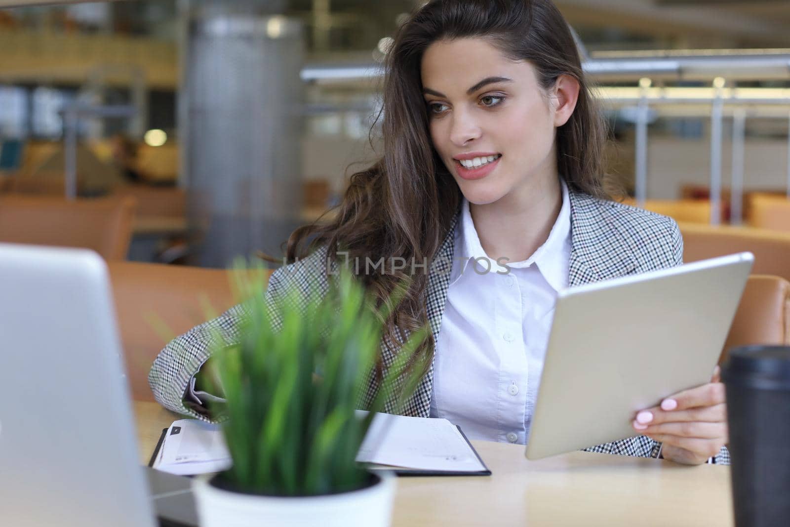 Young smiling businesswoman in office working on digital tablet. by tsyhun