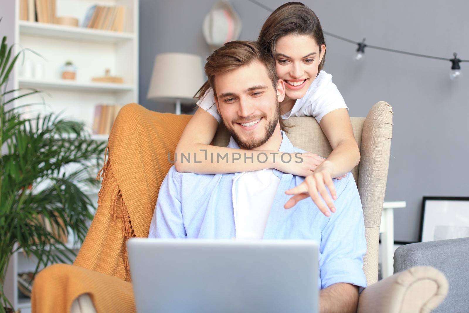 Young couple doing some online shopping at home, using a laptop on the sofa. by tsyhun