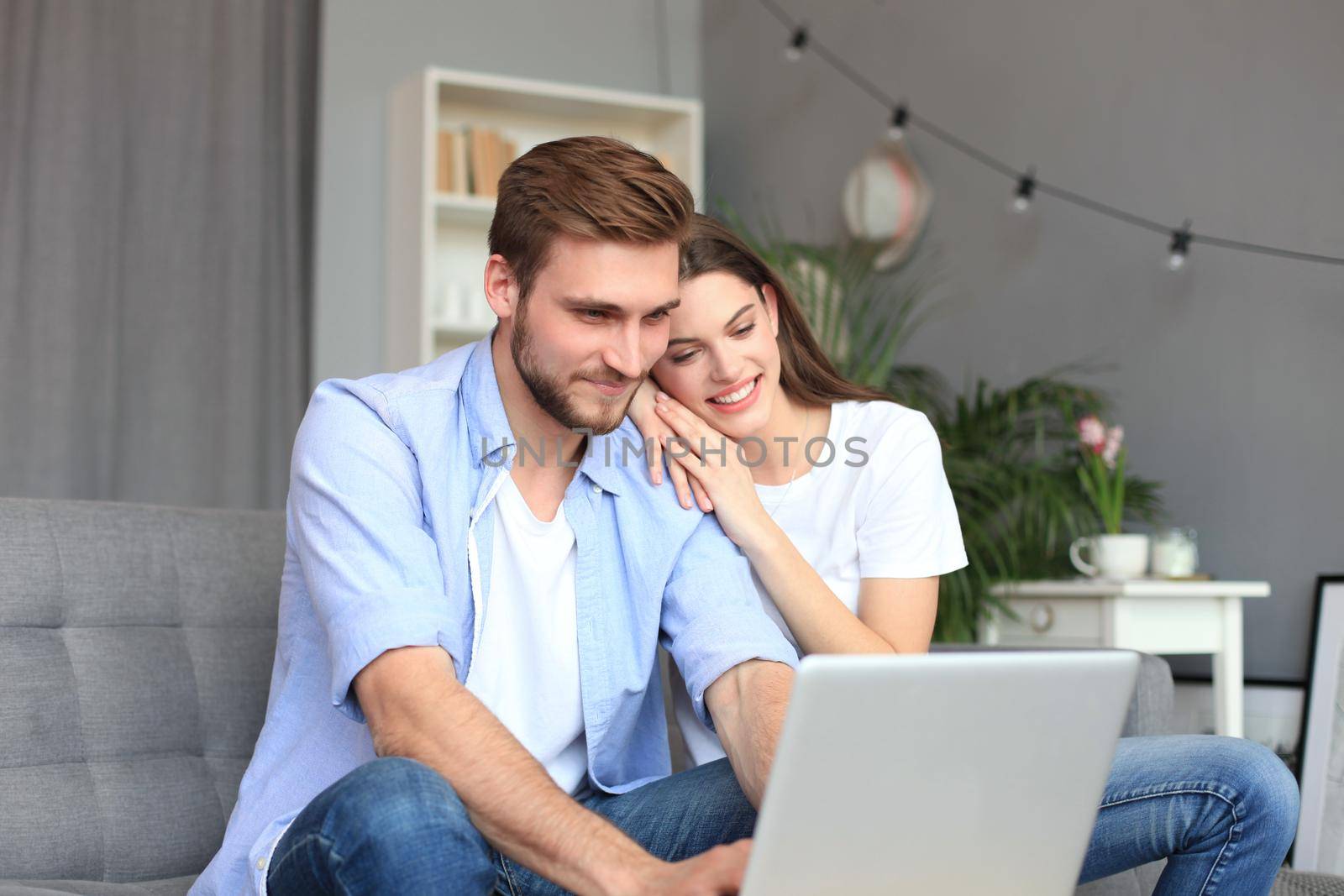 Young couple doing some online shopping at home, using a laptop on the sofa