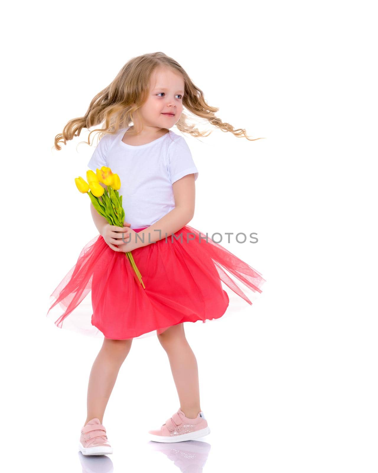 A cute little girl with a bouquet of tulips, in the spring in the studio. The concept of the awakening of nature after winter, the expectation of summer.