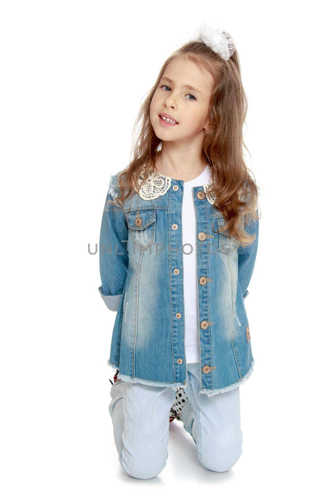 Portrait of adorable little girl in denim suit which is on the knees Studio - Isolated on white background