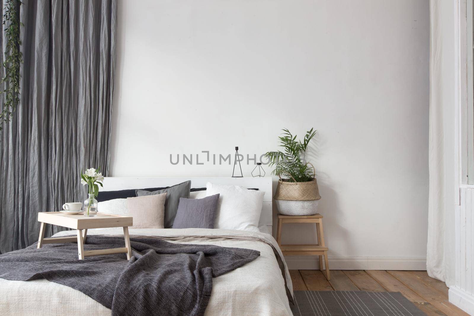 Interior of white and gray cozy bedroom with coffee on a tray