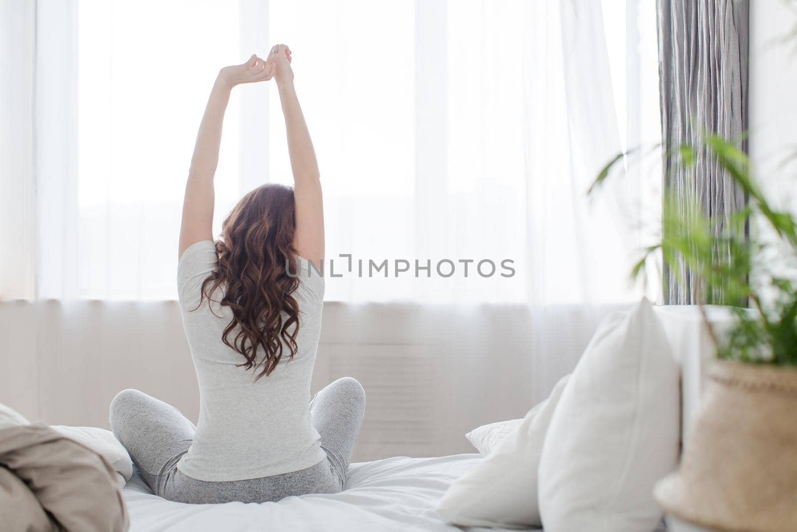 Female stretching sitting on bed in morning by Demkat