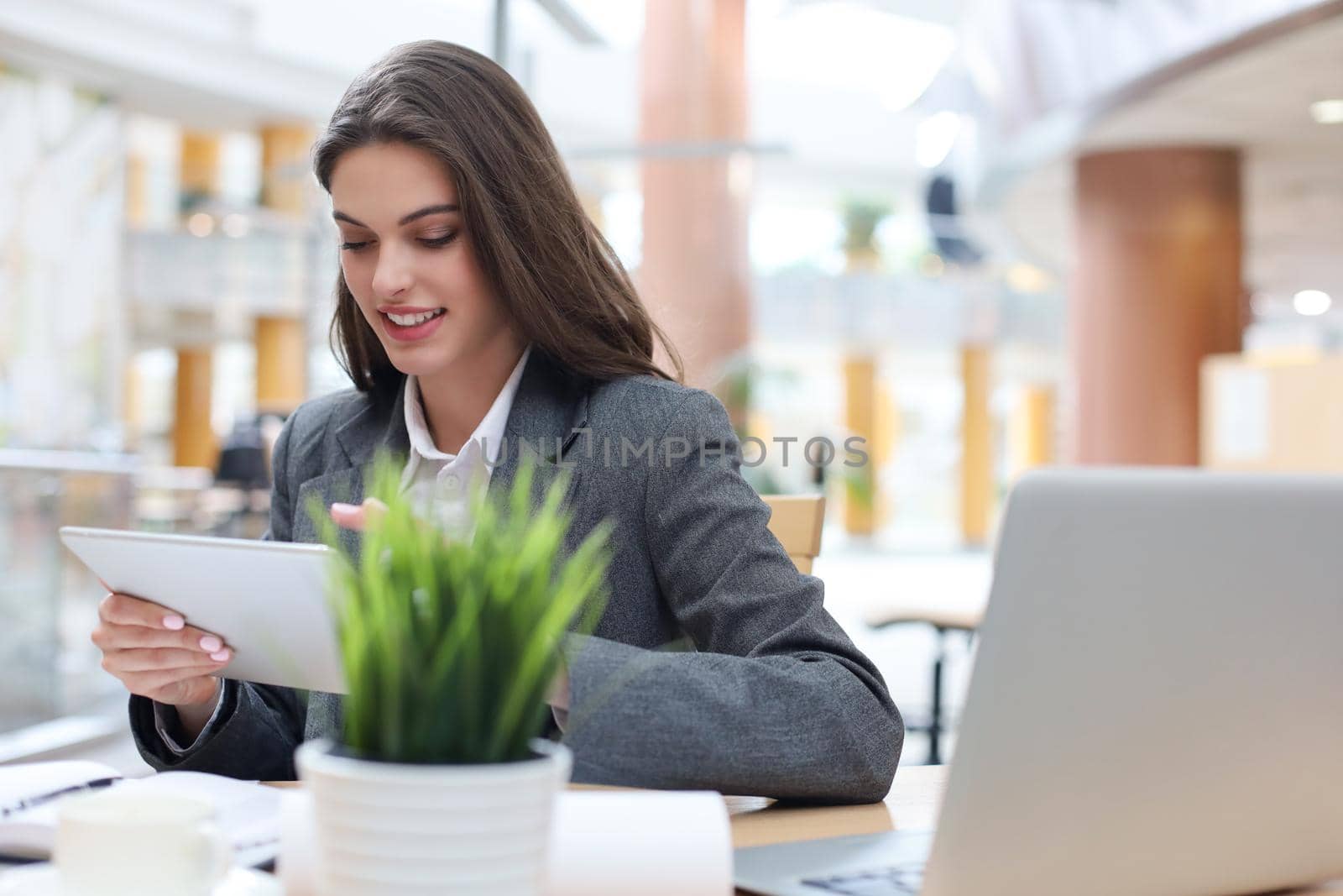 Young smiling businesswoman in office working on digital tablet
