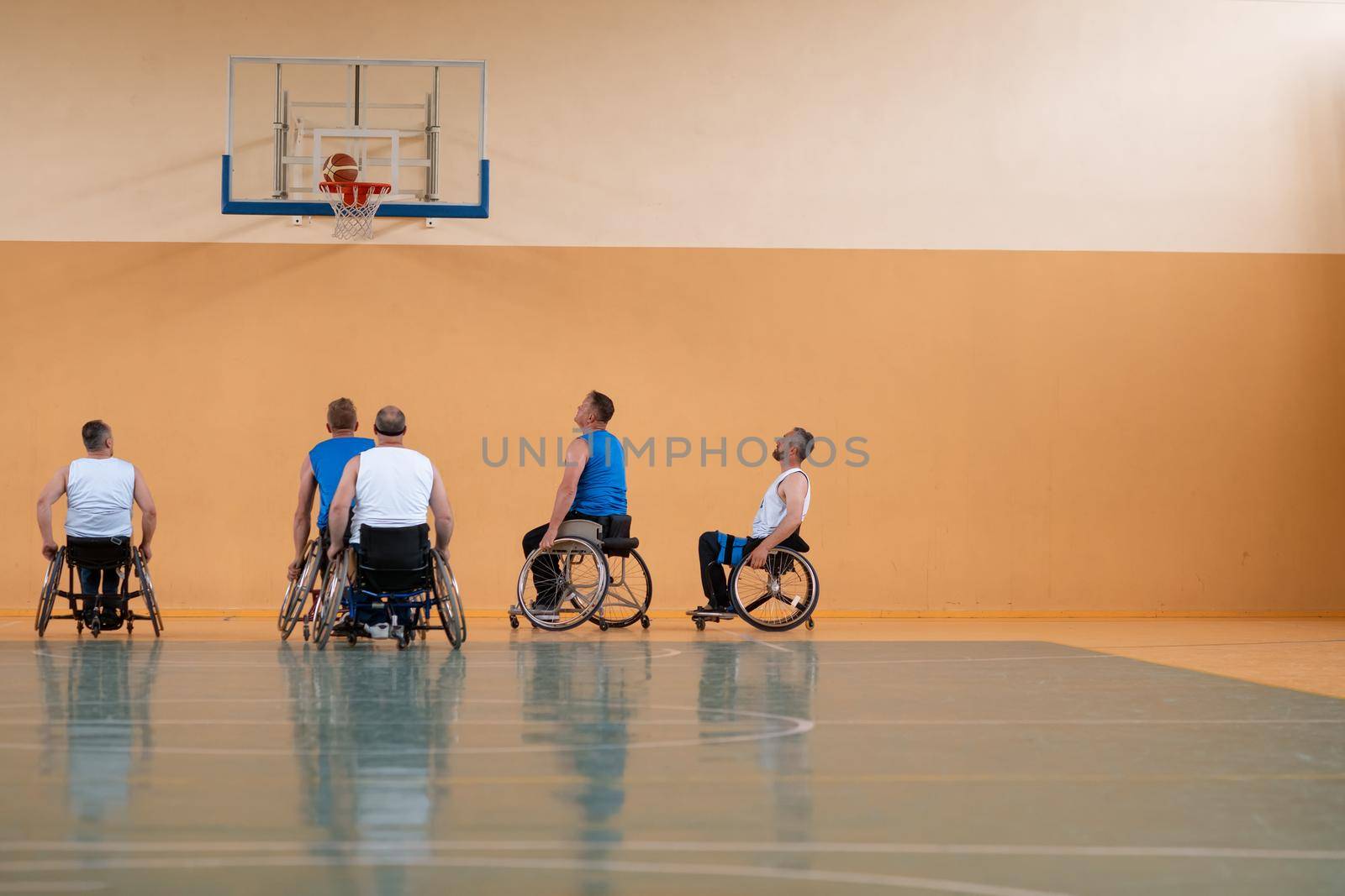 Disabled War veterans mixed race opposing basketball teams in wheelchairs photographed in action while playing an important match in a modern hall. High quality photo