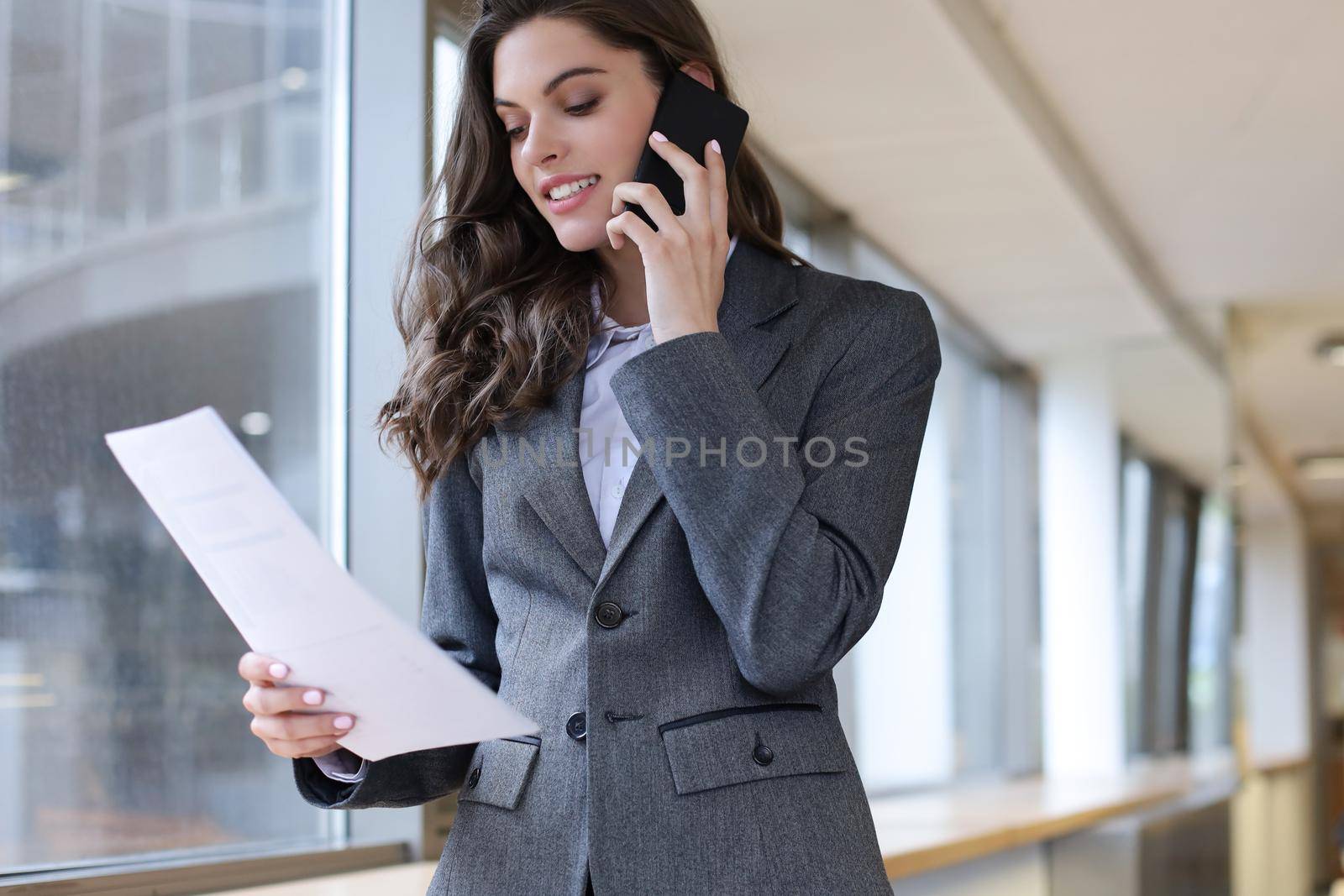 Young smiling business woman using smartphone in office