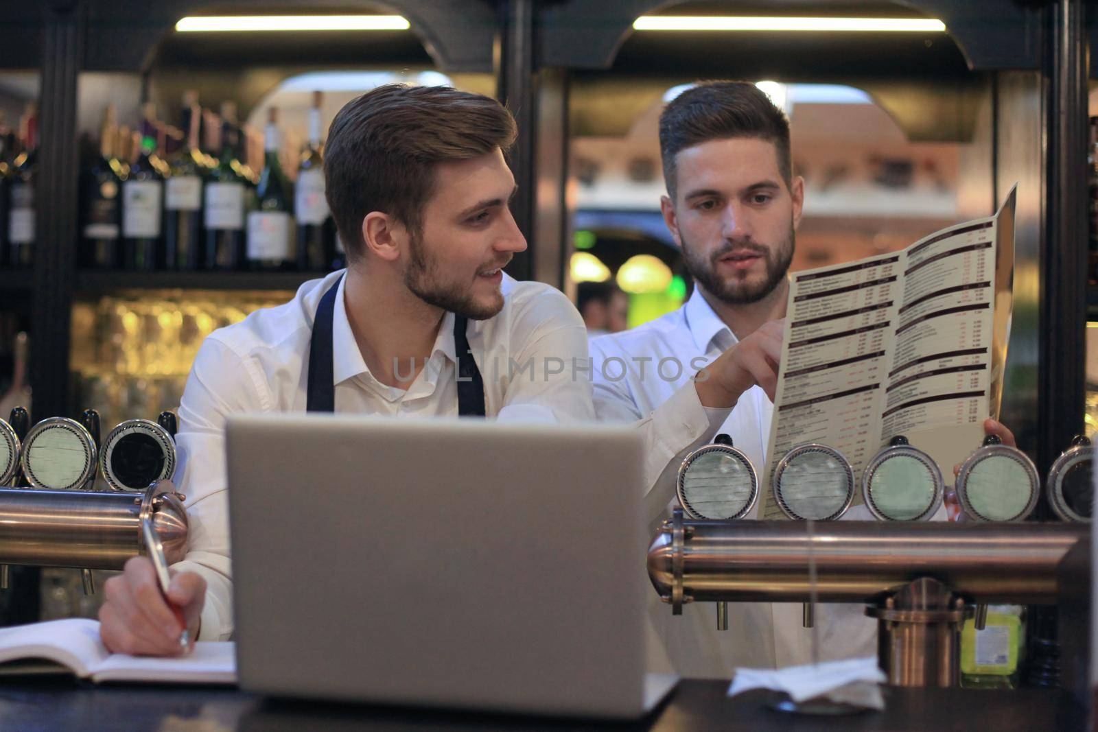 Two happy cafe managers working on laptop