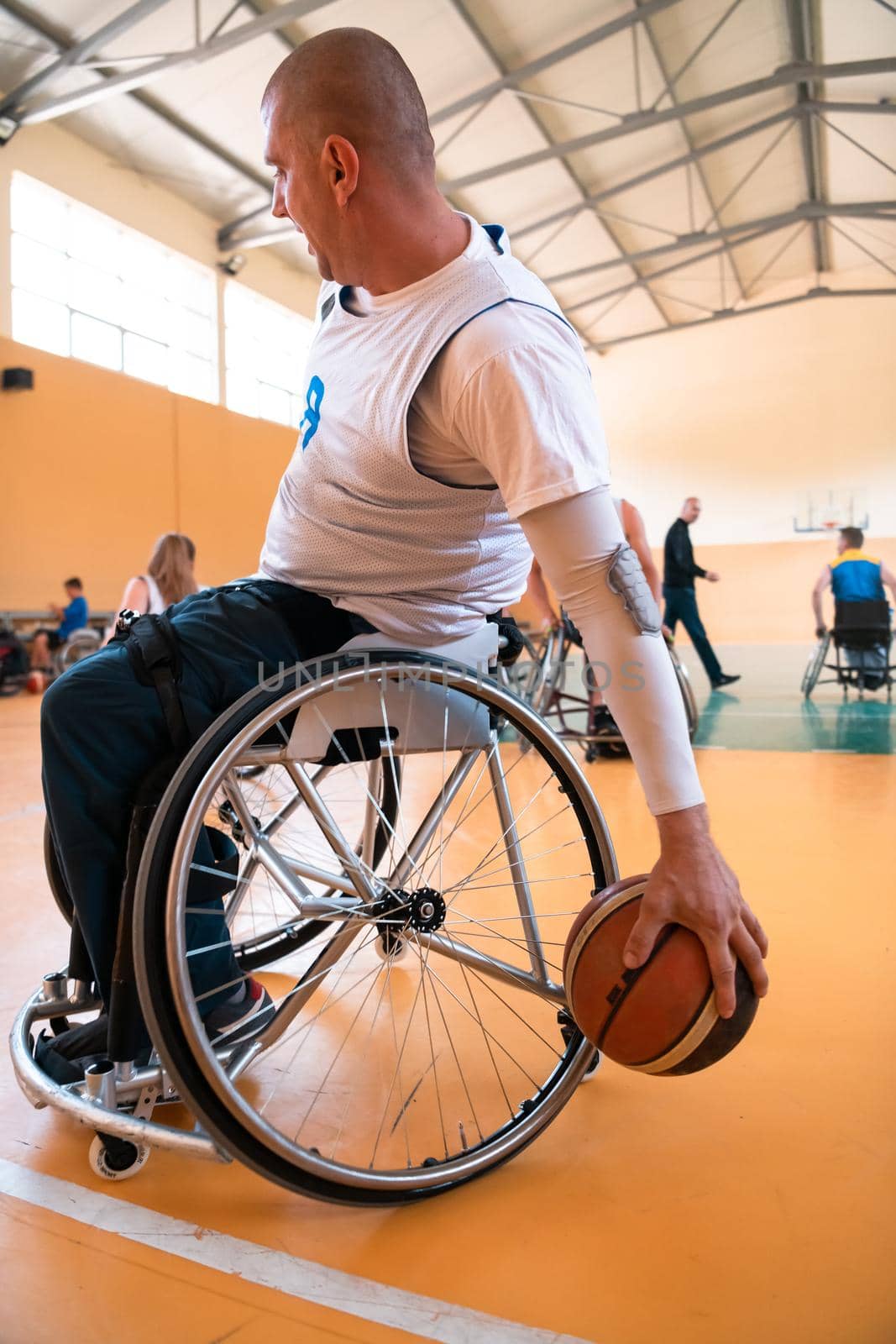 Close up photo of wheelchairs and handicapped war veterans playing basketball on the court. Selective focus. 
