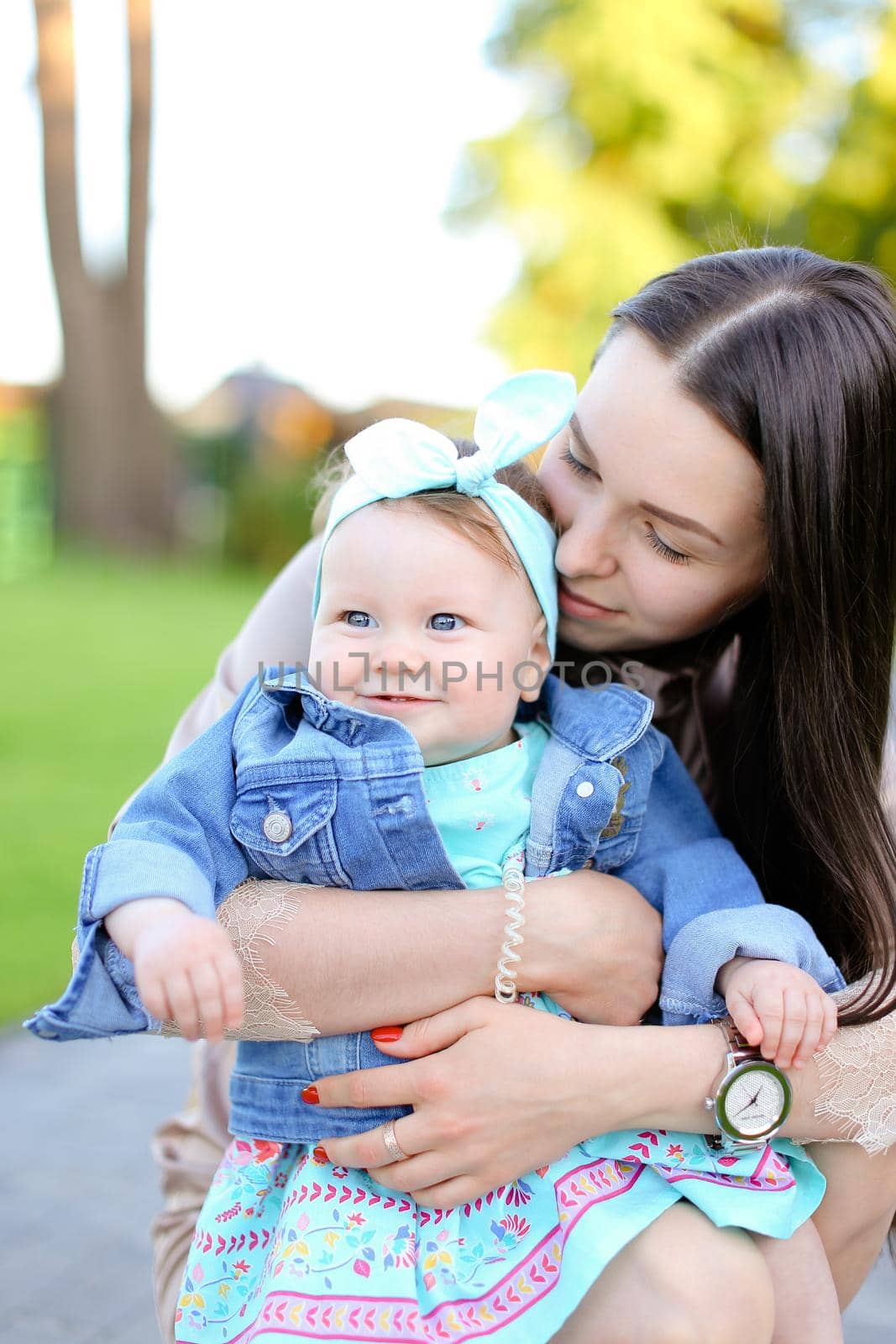 Young european woman holding little daughter wearing jeans jacket. Concept of motherhood and children.