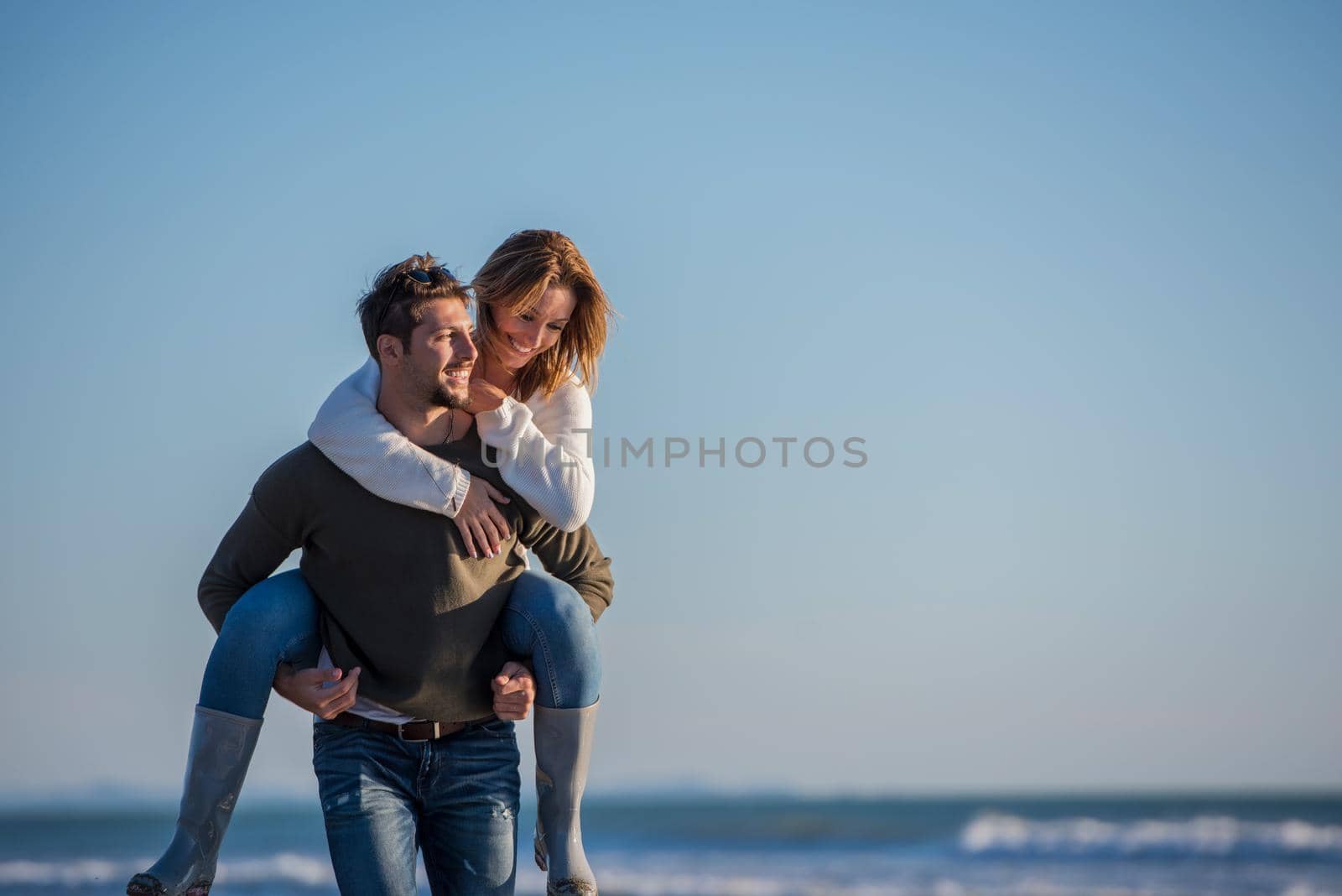 Men Giving Piggy Back Rides to his girlfriend At Sunset By The Sea, autumn time