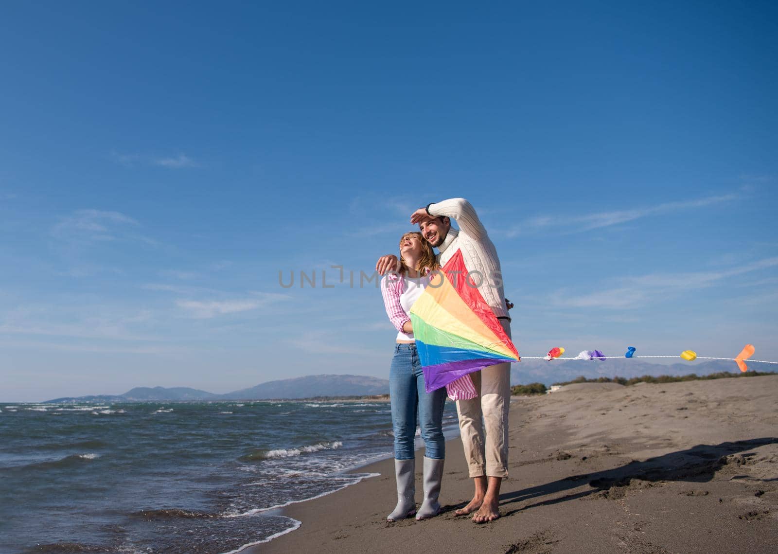 Young Couple having fun and Playing With A Kite On The Beach at autumn day