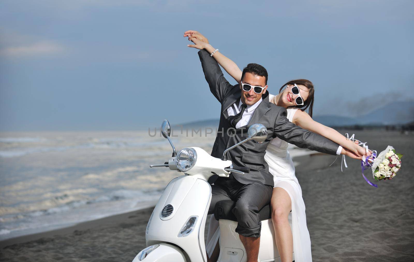 wedding sce of bride and groom just married couple on the beach ride white scooter and have fun