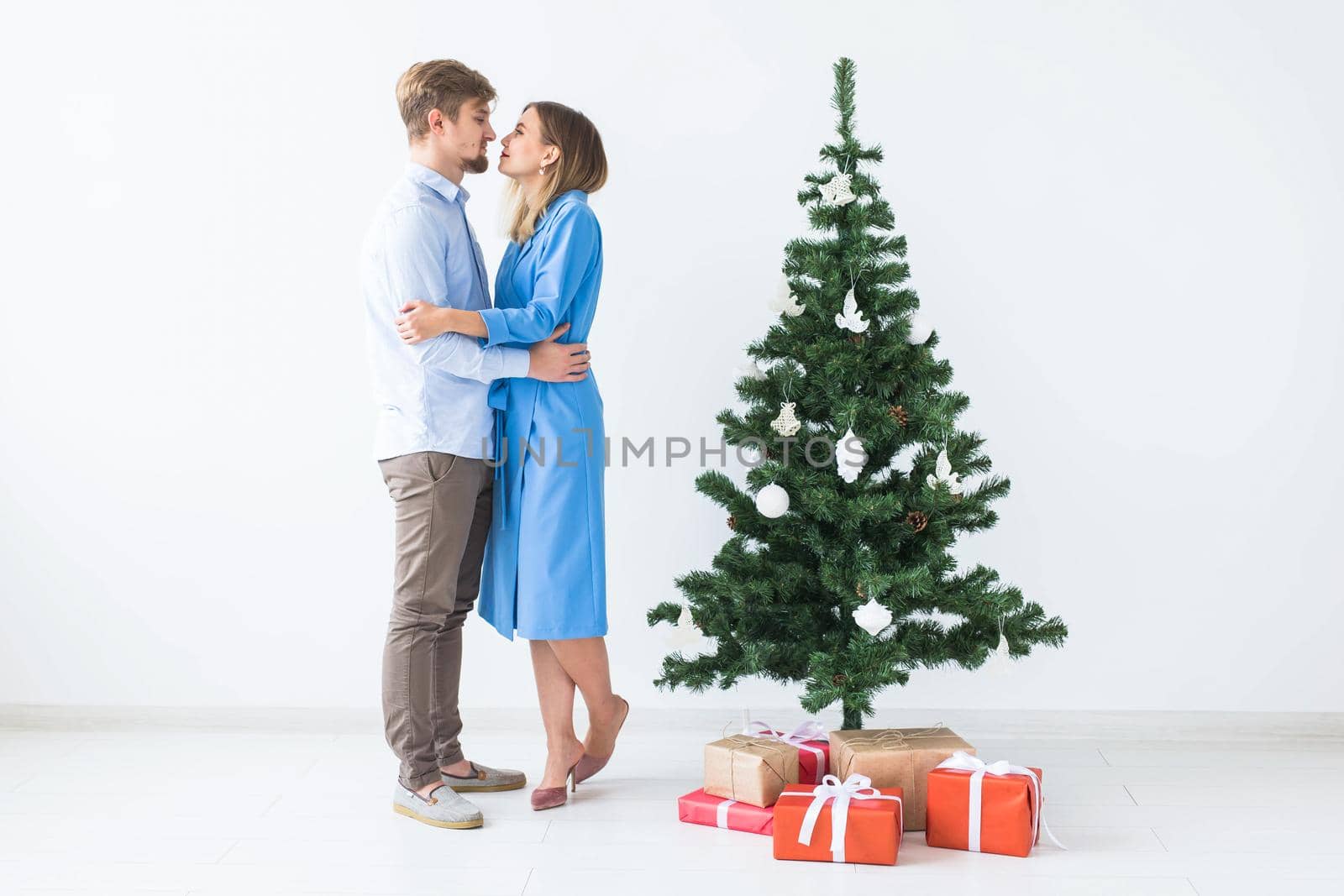 Holidays and festive concept - Young happy couple near a Christmas tree on white background by Satura86