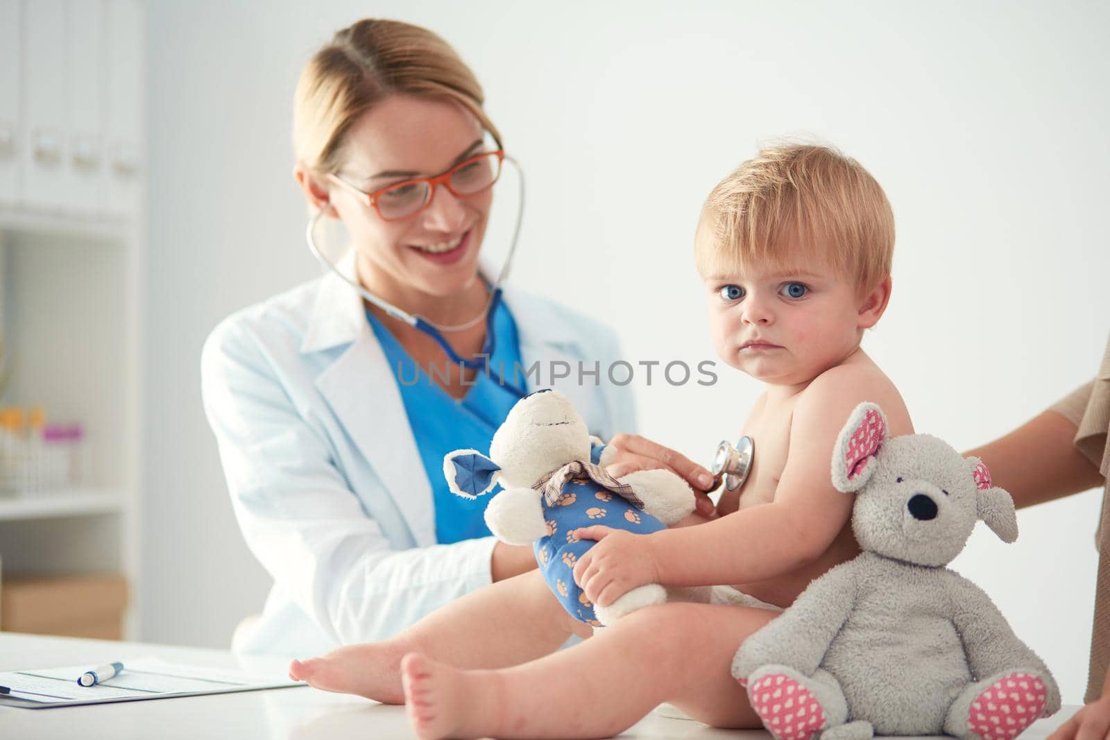 Female doctor is listening kid with a stethoscope in clinic.