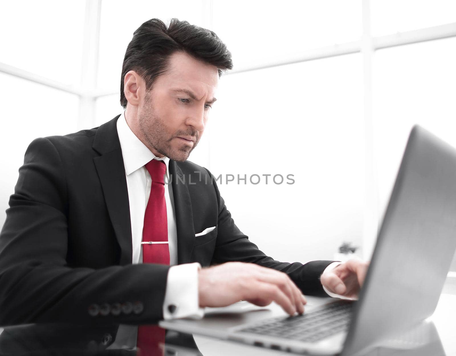 Businessman typing on a laptop, sitting at his Desk.photo with copy space