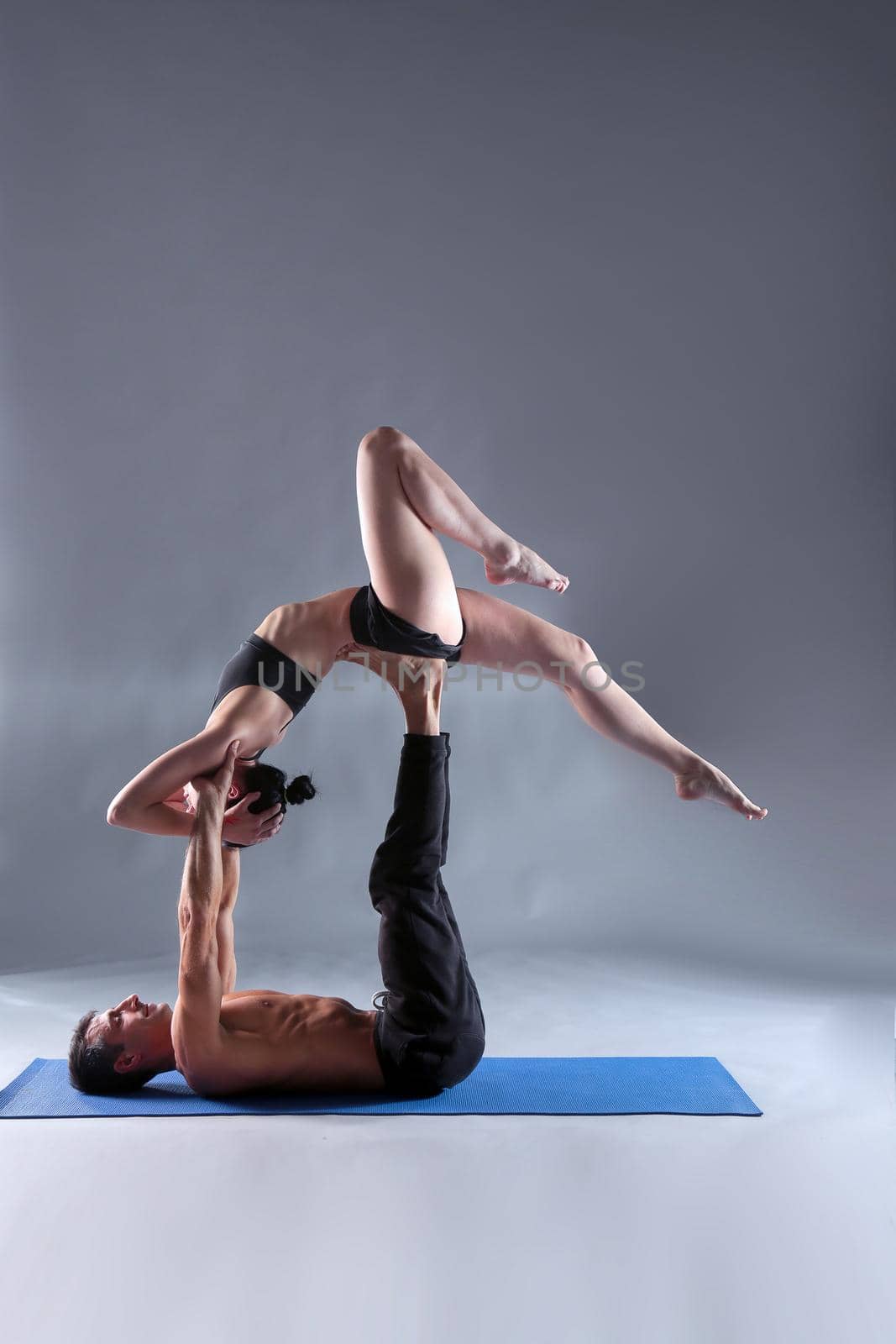Young couple practicing acro yoga on mat in studio together. Acroyoga. Couple yoga. Partner yoga