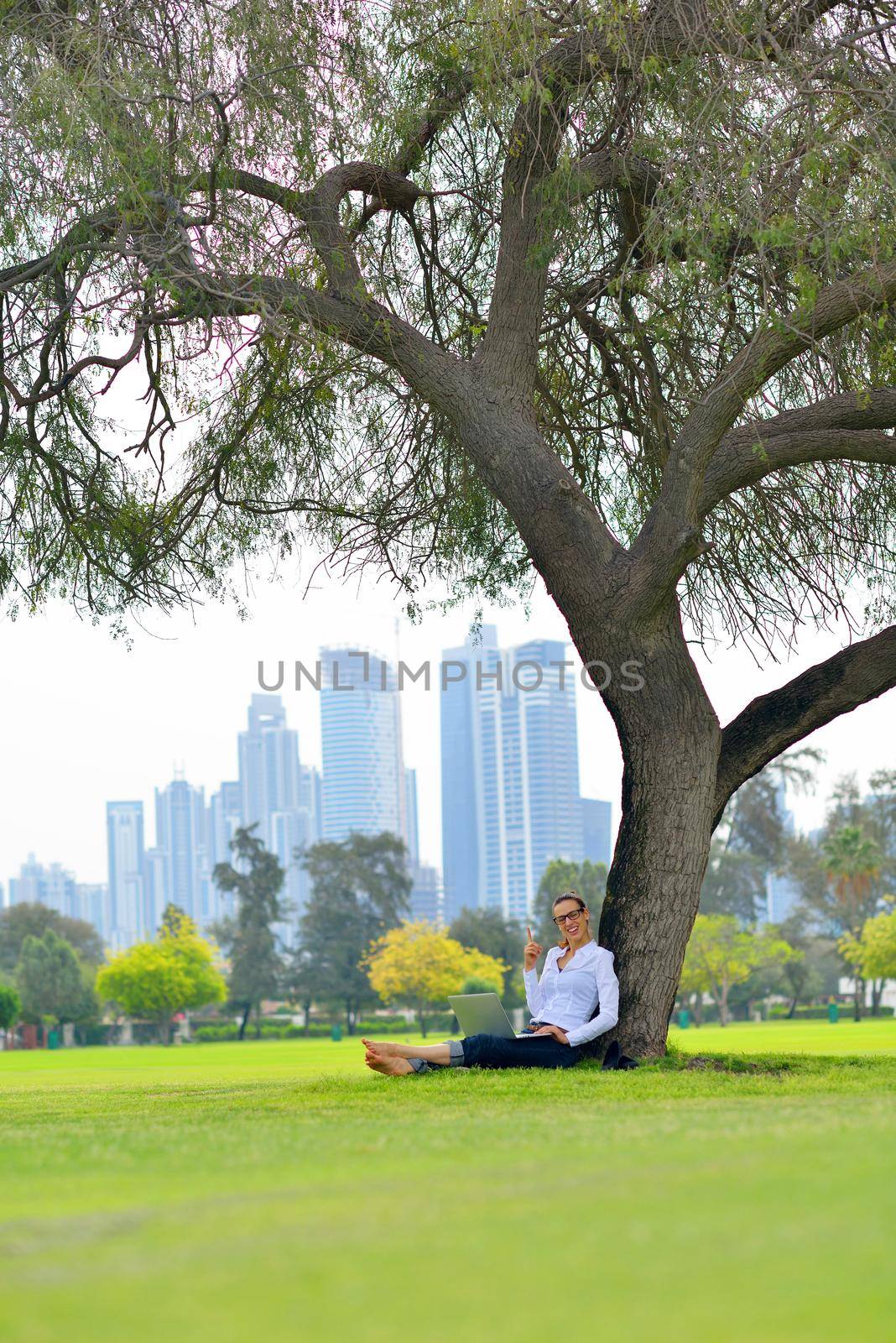 happy young student woman with laptop in city park study