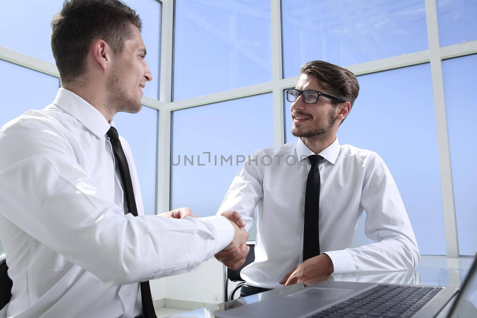 Two businessmen are sitting in the office and discussing the conclusion of a new deal