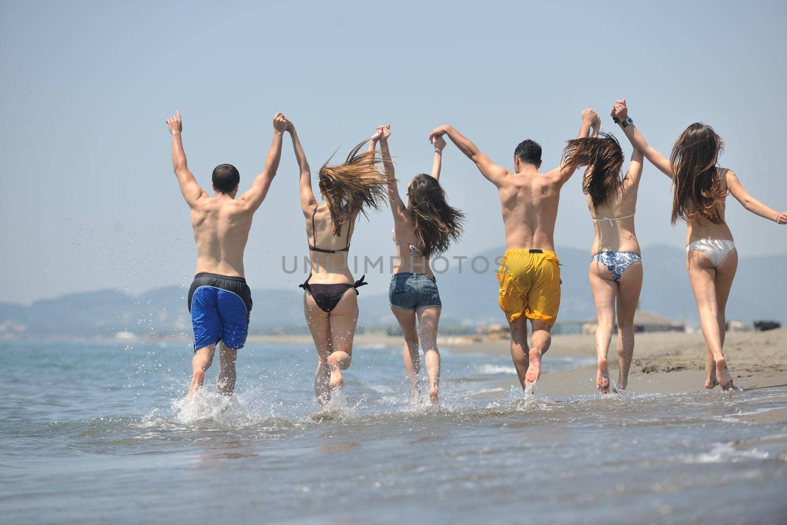 happy people group have fun and running on beach by dotshock