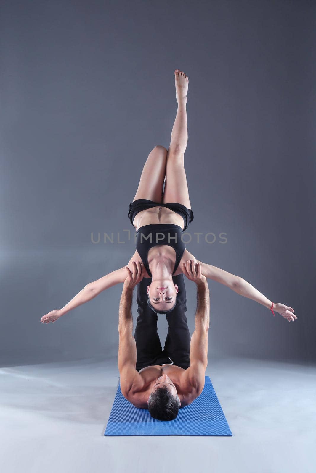 Young couple practicing acro yoga on mat in studio together. Acroyoga. Couple yoga. Partner yoga