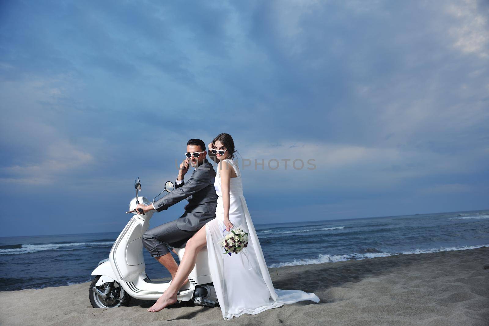 wedding sce of bride and groom just married couple on the beach ride white scooter and have fun