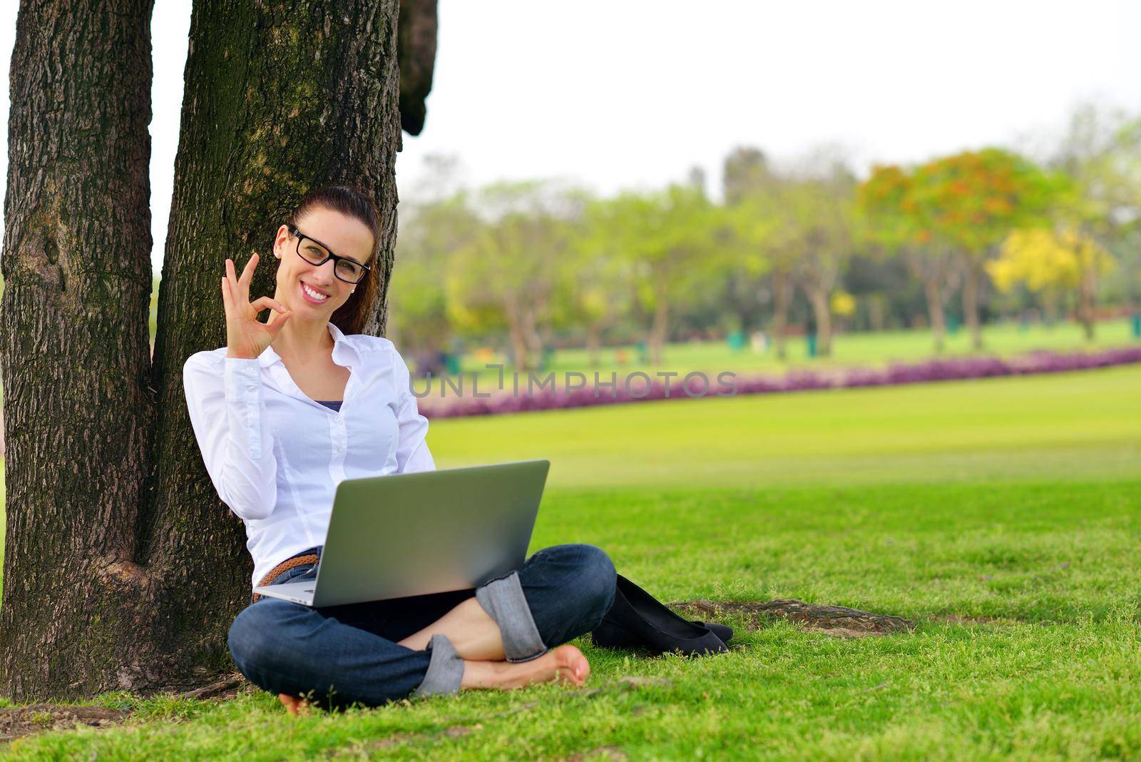 happy young student woman with laptop in city park study