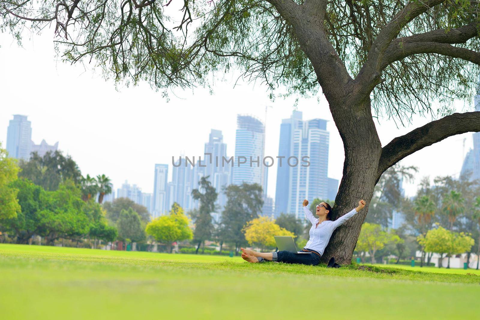 happy young student woman with laptop in city park study