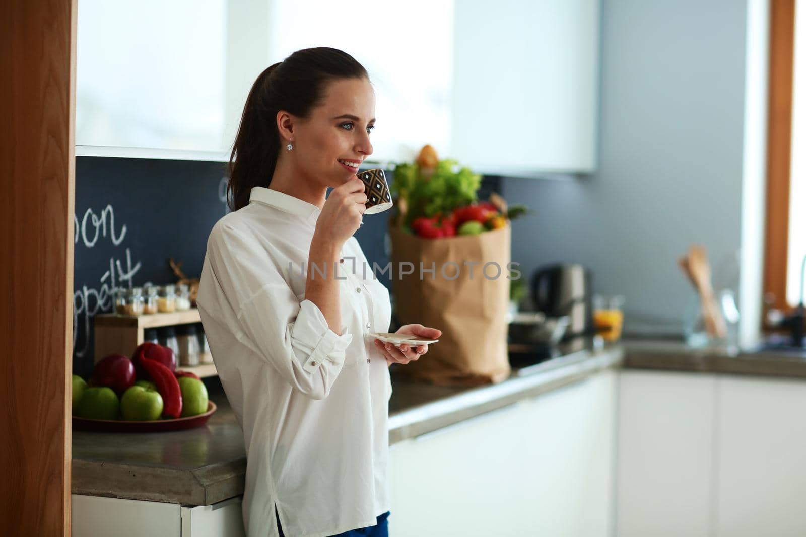 Happy woman drinking tea in the kitchen at home.