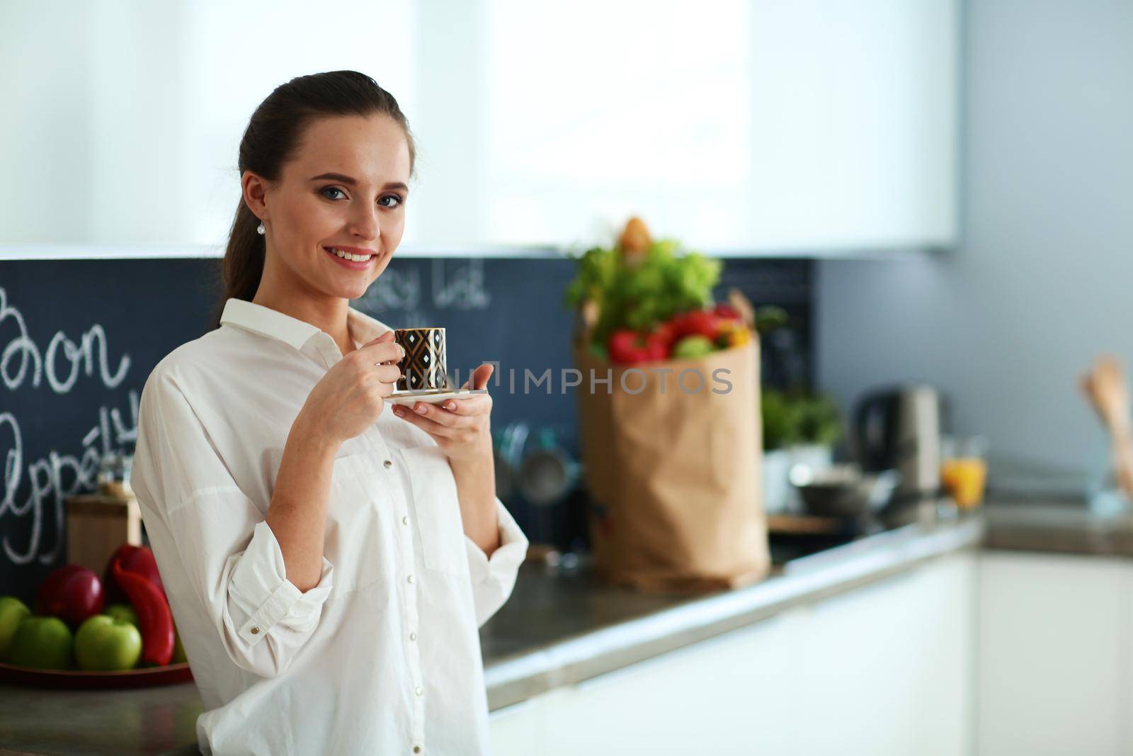 Happy woman drinking tea in the kitchen at home by lenetstan