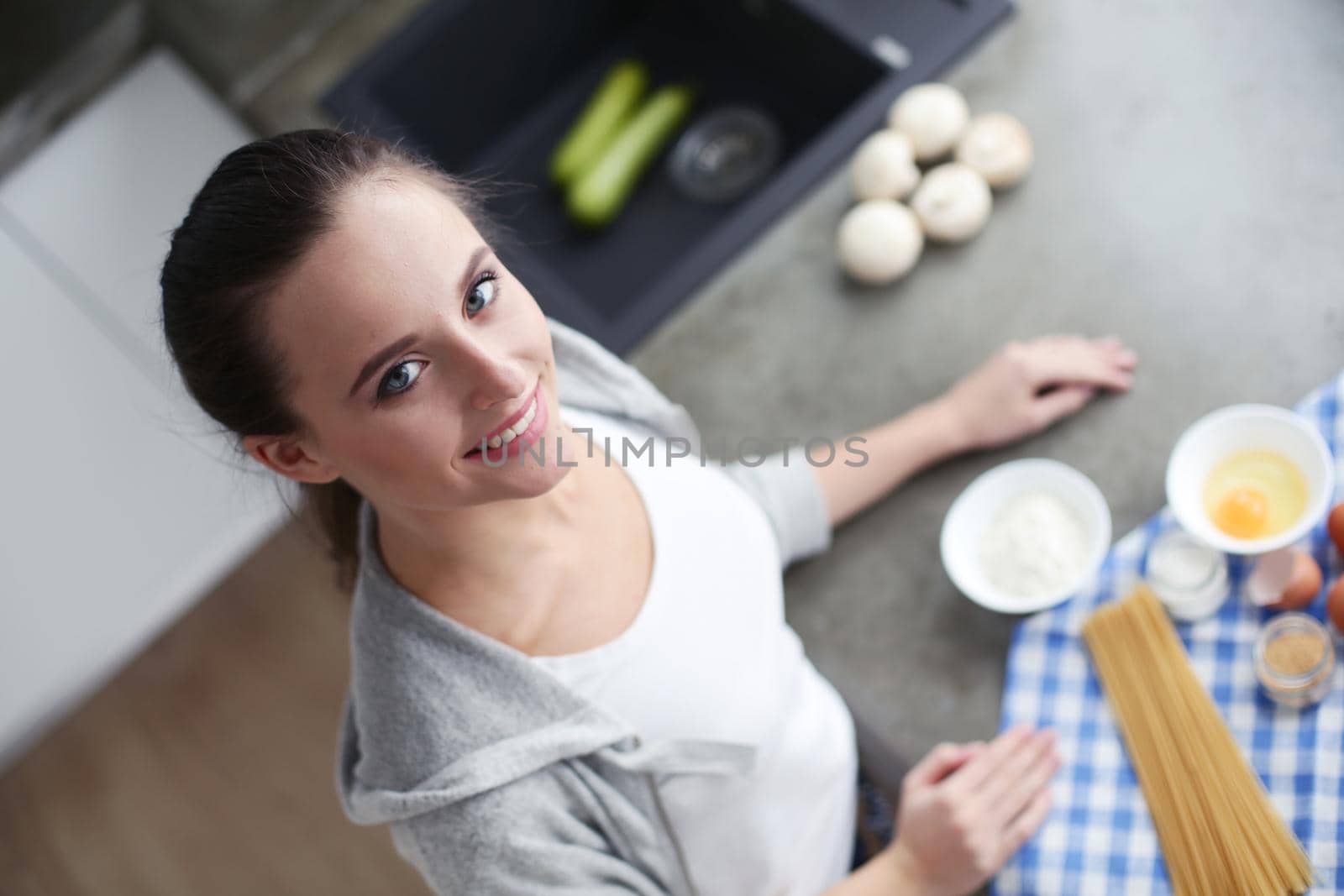 Beautiful woman cooking cake in kitchen standing near desk