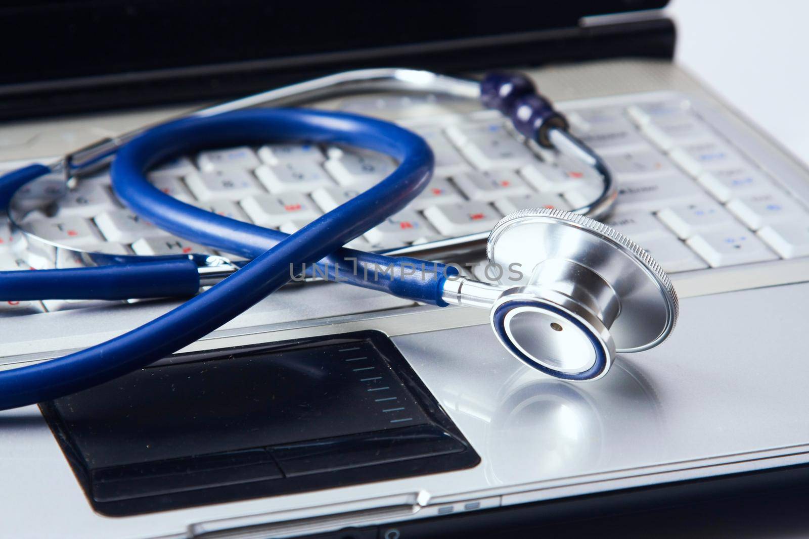 Stethoscope with clipboard and laptop on the desk.