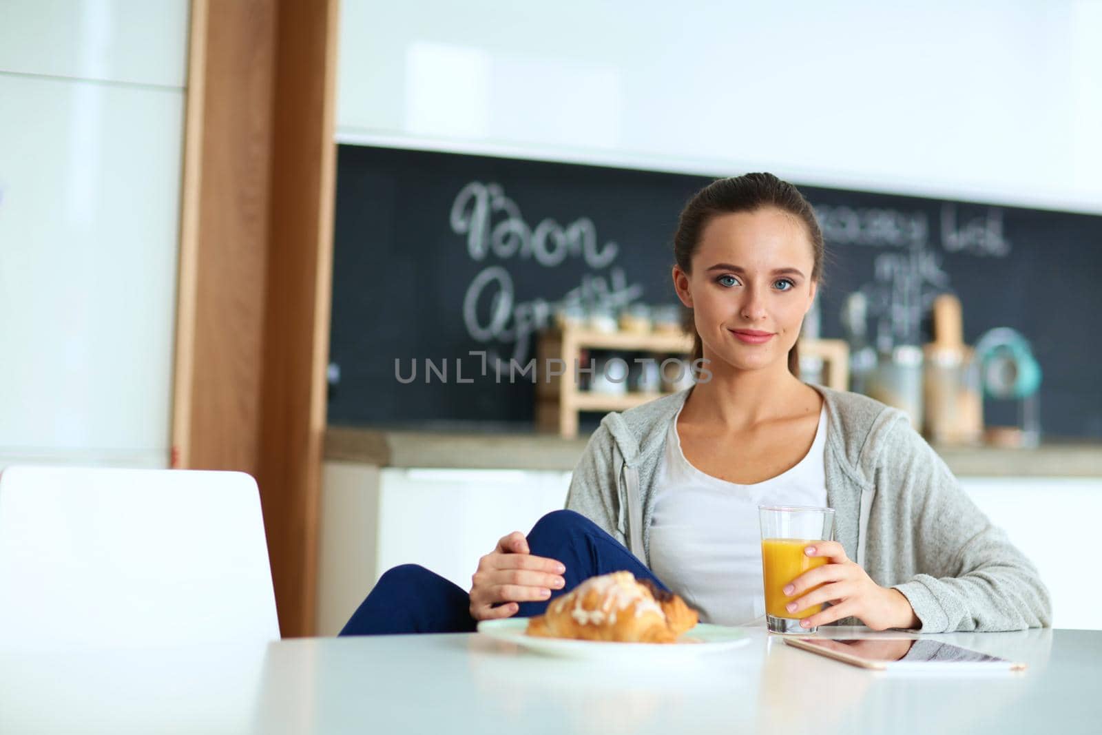 Young woman with orange juice and tablet in kitchen by lenetstan