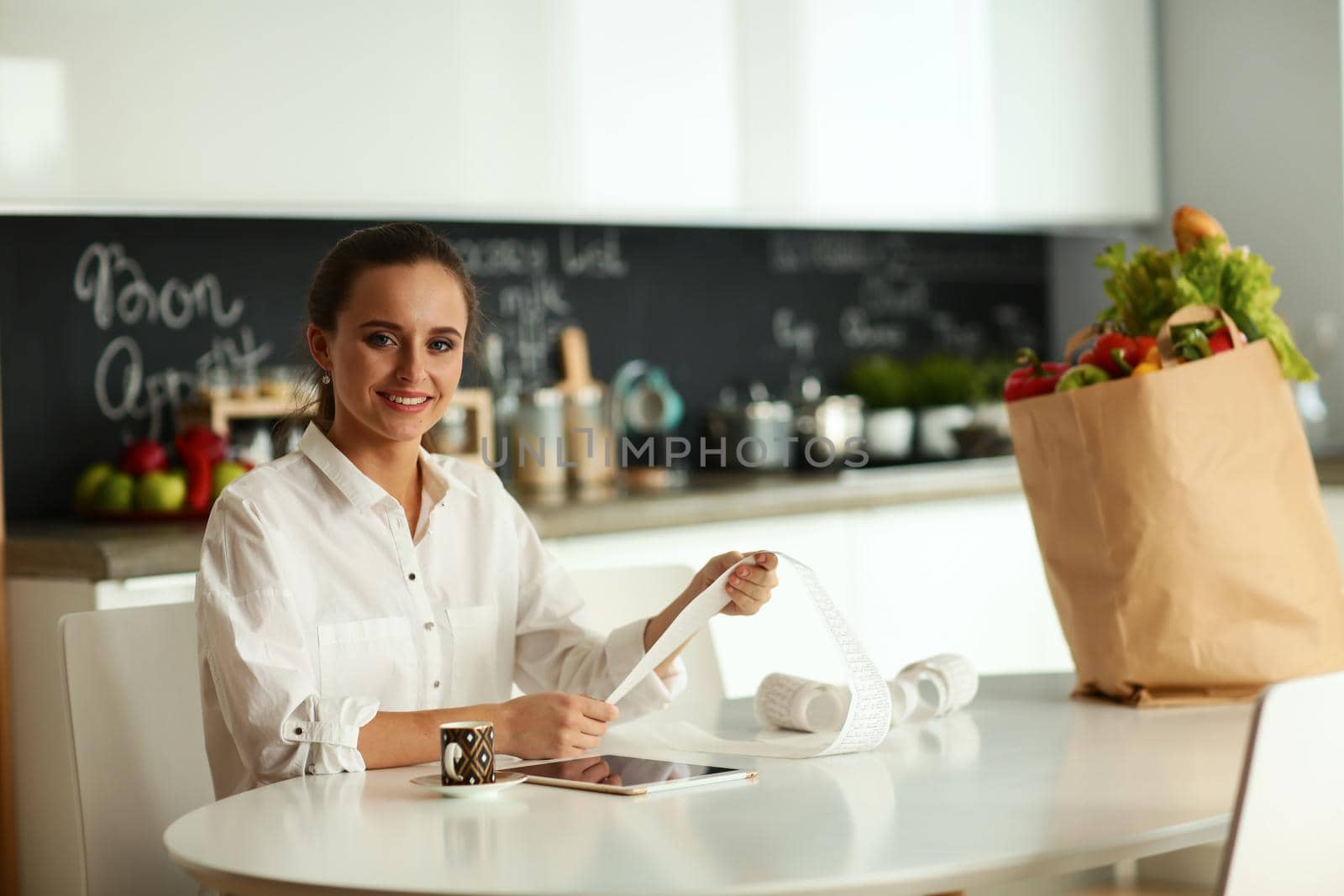 Young woman planning expenses and paying bills on her kitchen by lenetstan